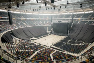 Vue panoramique du Stade de France lors d'un concert avec tribunes masquées par des bâches noires derrière la scène